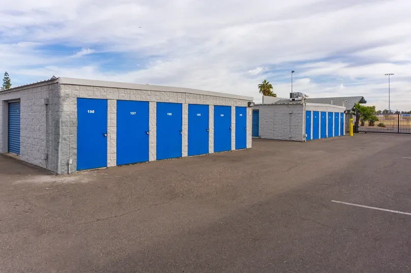 Drive-up storage units with blue roll-up doors and wide access lanes